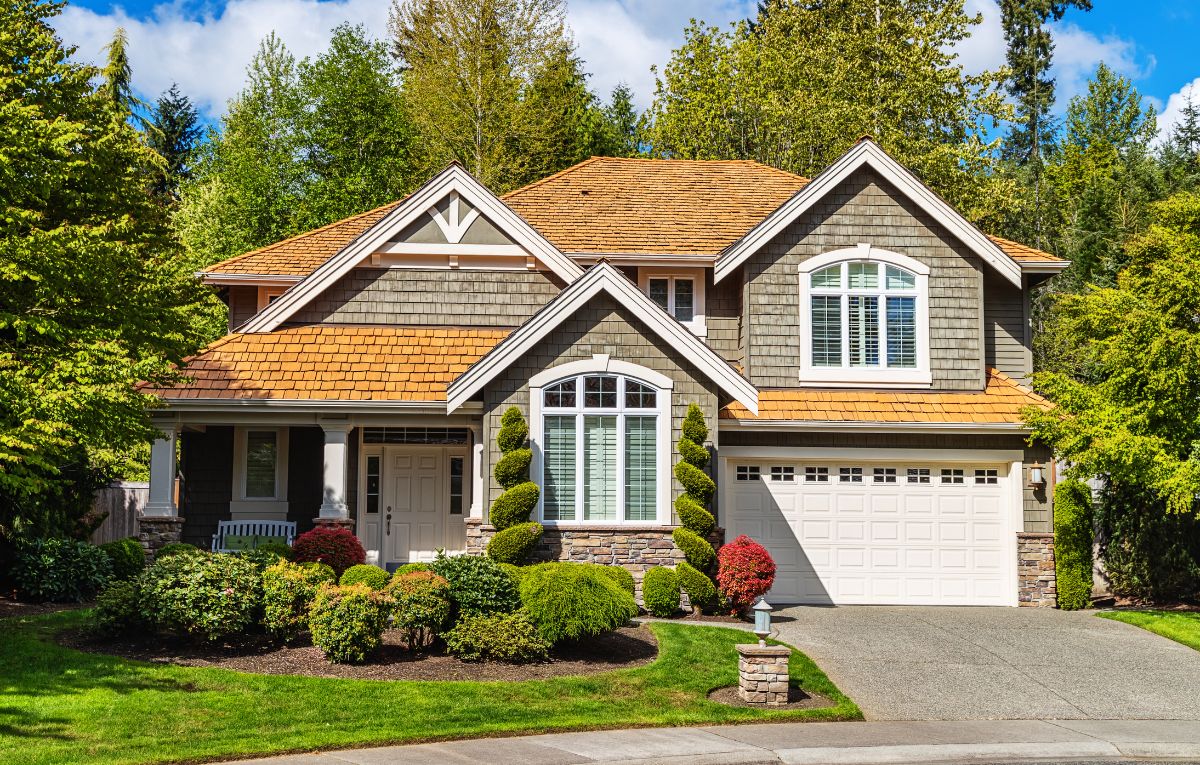 a two story house with lots of trees surrounding the house.