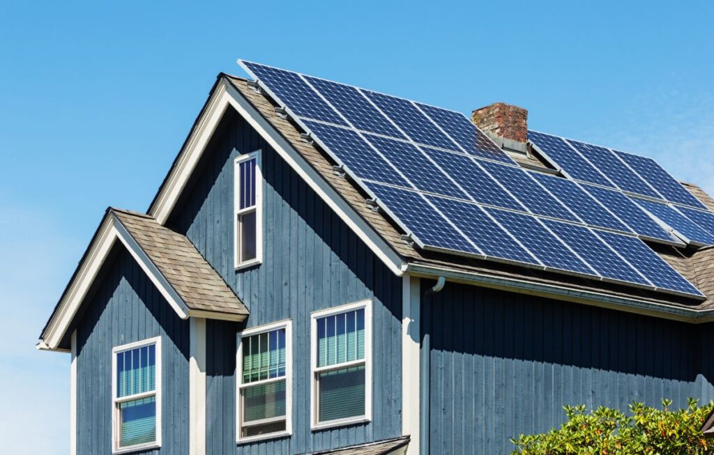 Blue-gray house with solar panels on shingled roof