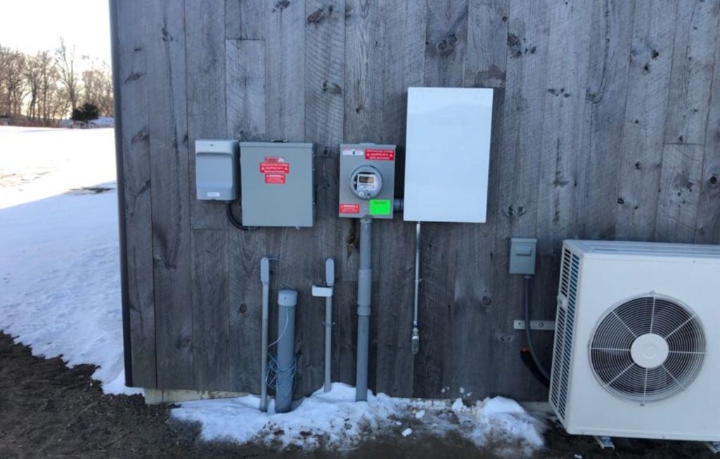 Electrical utility equipment and mini-split heat pump on building exterior