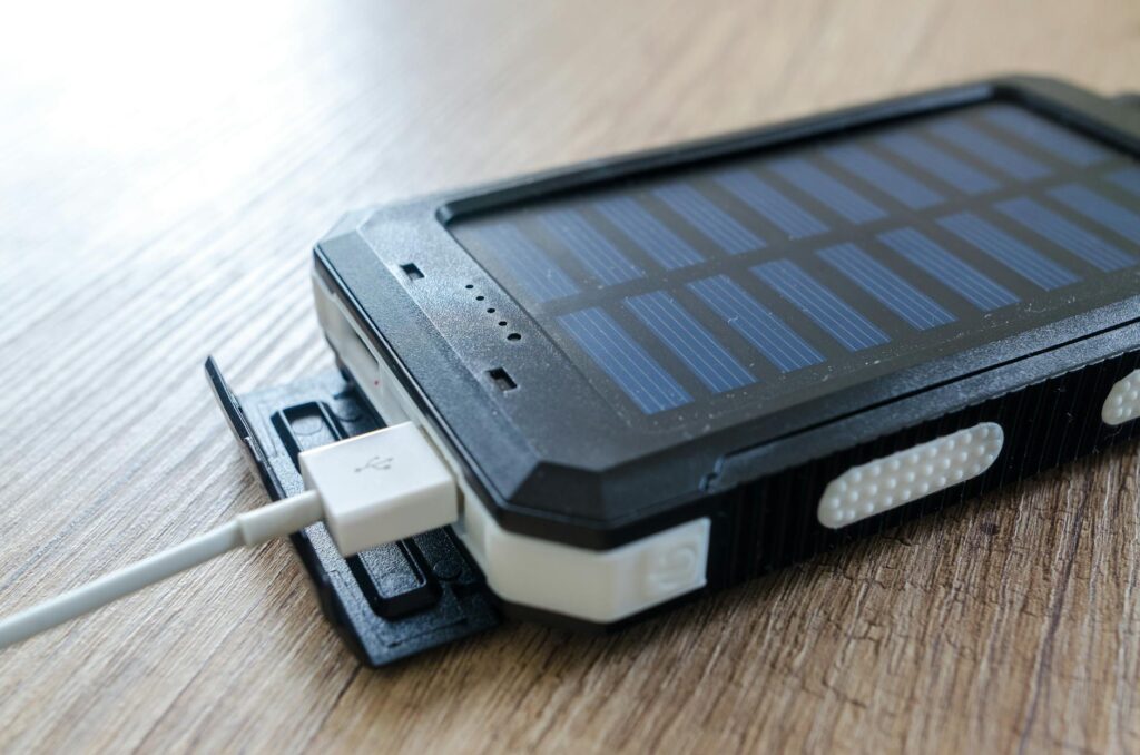 Close-up of a portable solar power bank charging via USB, illustrating how to add battery storage to a solar panel system