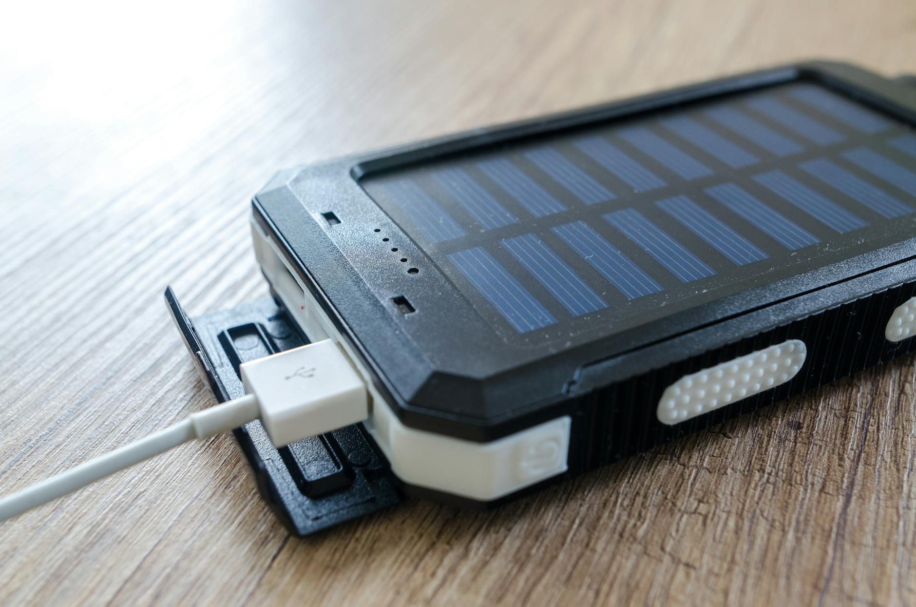 Close-up of a portable solar power bank charging via USB, illustrating how to add battery storage to a solar panel system