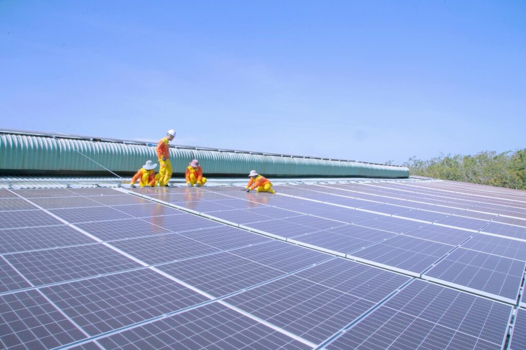 Professional maintenance crew inspecting a large rooftop solar array as part of a solar panel maintenance guide