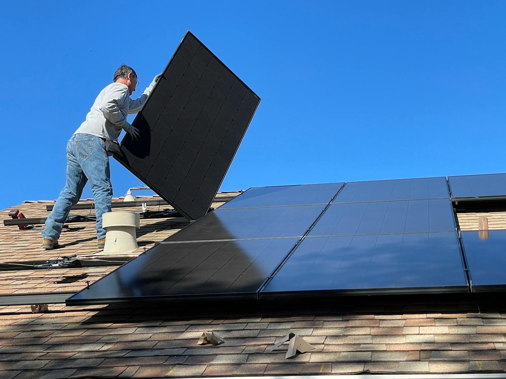 Professional installer placing a high-efficiency solar panel onto a roof