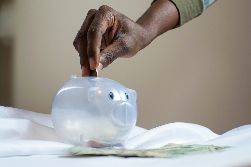 Person putting a coin into a piggy bank next to cash, representing savings from a prepaid solar lease