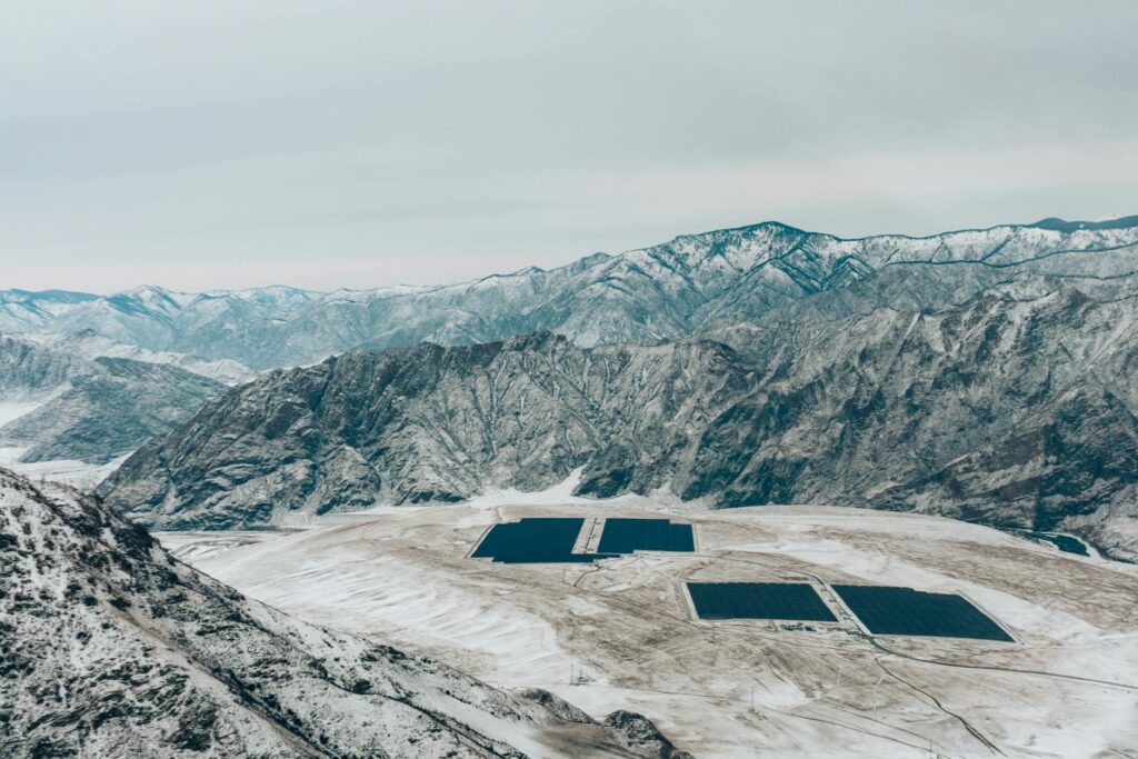 Large-scale solar farm and battery storage installation located in a snowy mountain valley, illustrating utility-scale renewable energy storage