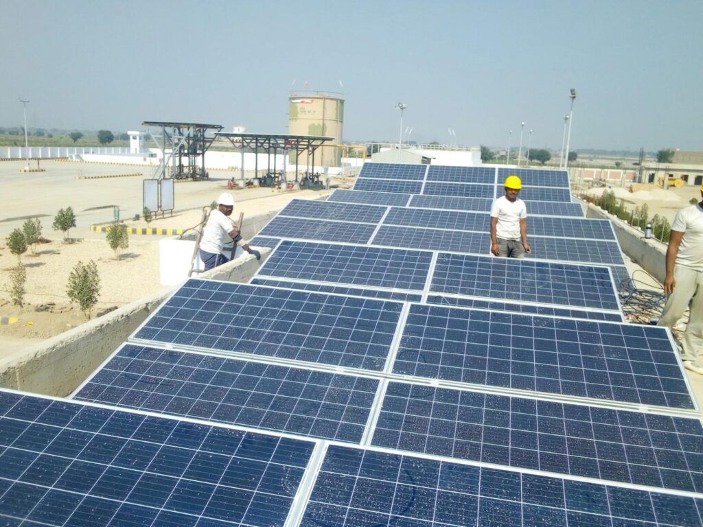 Workers installing solar panels on a flat commercial roof, representing the factors that impact solar installation costs