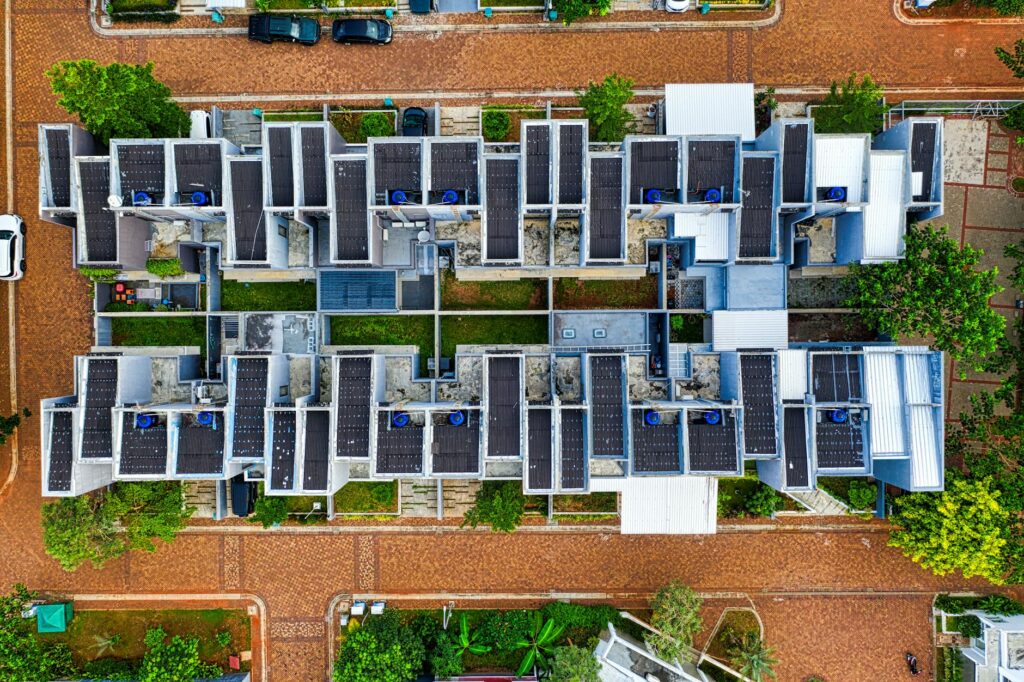 Aerial top-down view of a modern residential complex featuring flat-roof solar mounting systems on multiple units