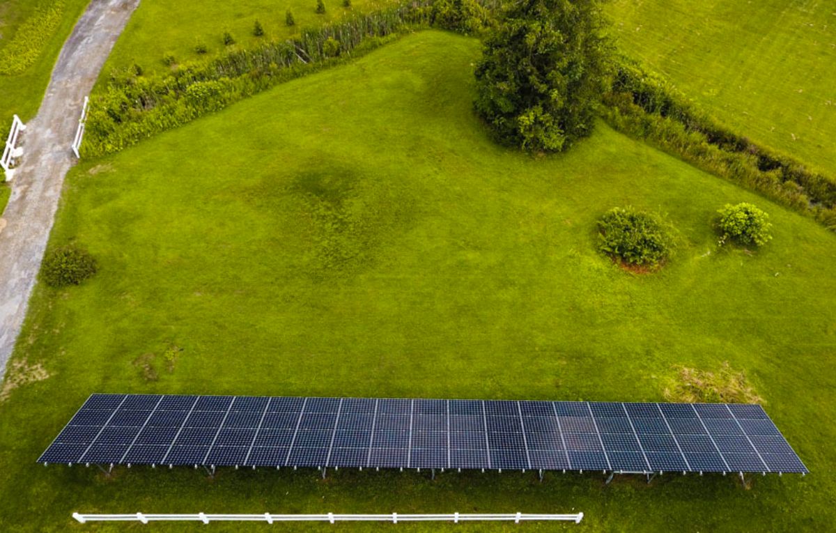 Ground-mounted solar panel array on a green farm field