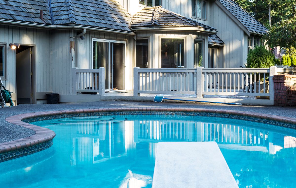 Backyard swimming pool beside a home, representing solar pool heating maintenance